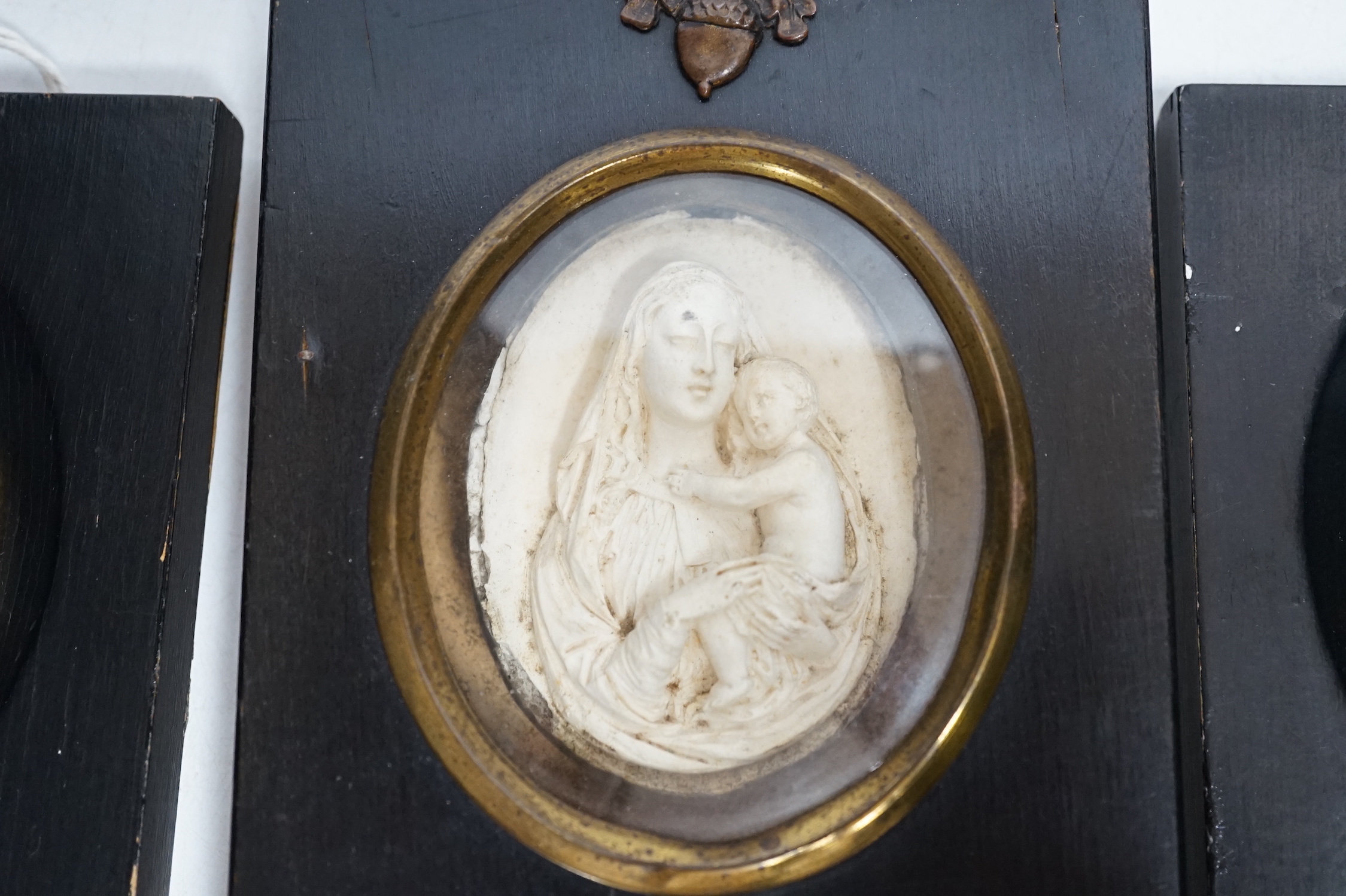 Three miniature reverse glass painted silhouettes, a relief plaque of the virgin and child and a watercolour portrait pendant